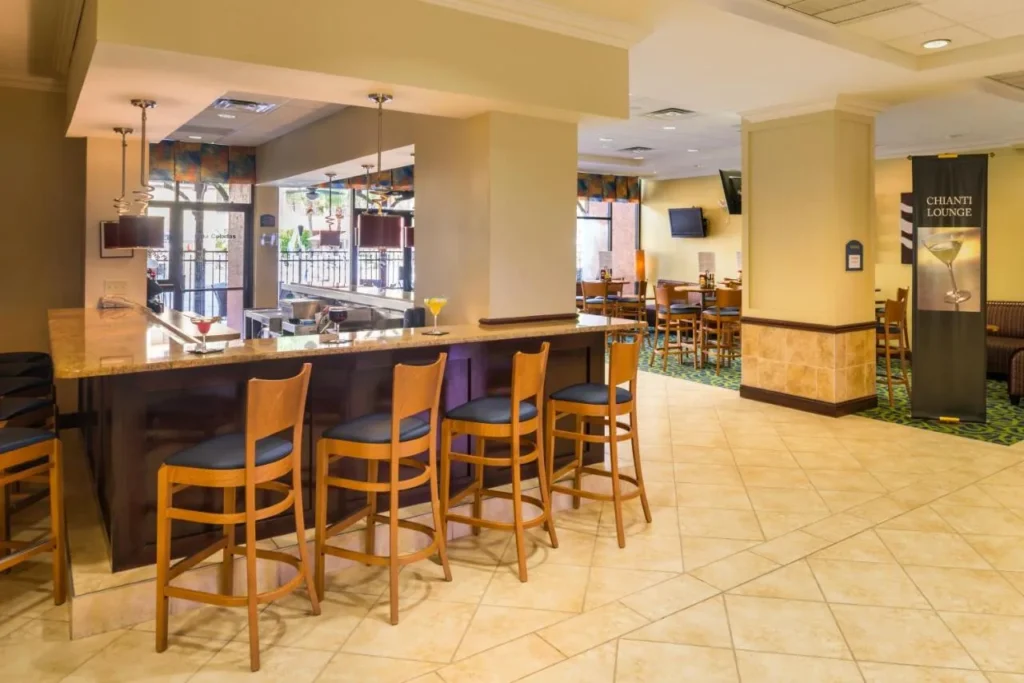 Chianti's Lounge bar con taburetes y asientos en el vestíbulo en Holiday Inn & Suites Orlando SW