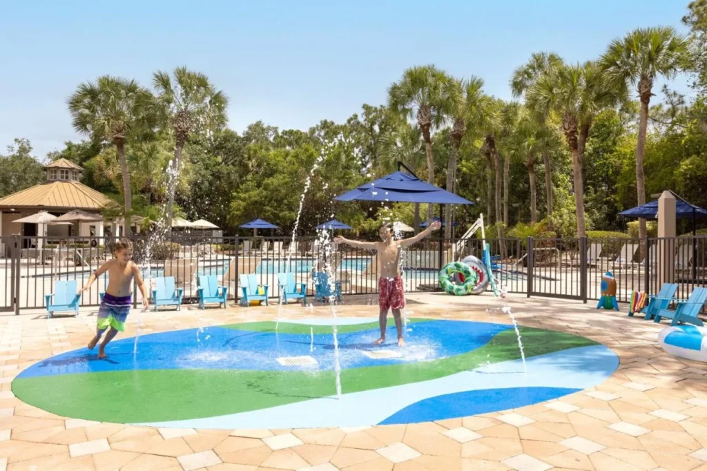 Ni&ntilde;os jugando en las fuentes de splash pad junto a la piscina en DoubleTree Suites by Hilton Orlando en Disney Springs