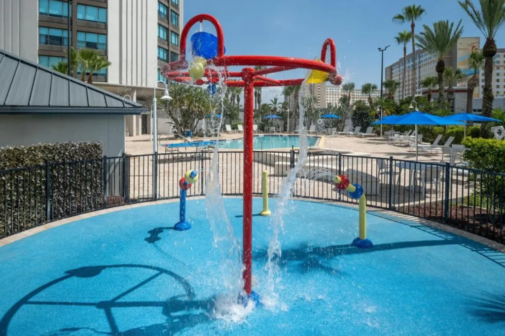 Almohadilla de salpicaduras para niños con rociadores de agua rojos y amarillos junto a la piscina en Four Points I-Drive