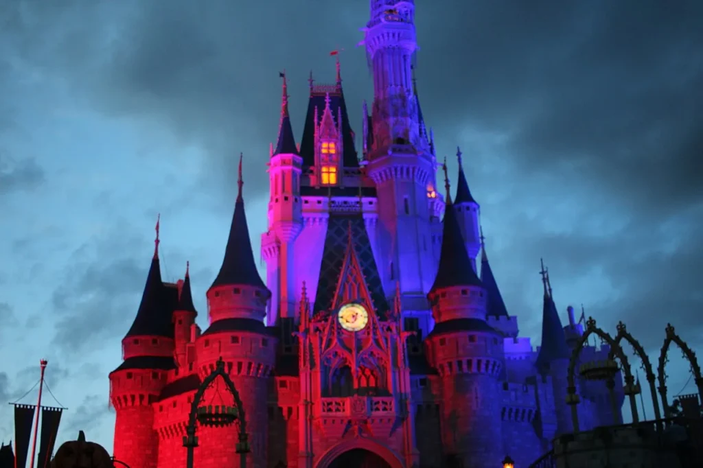 Cinderella Castle at Magic Kingdom lit purple and red under a stormy evening sky