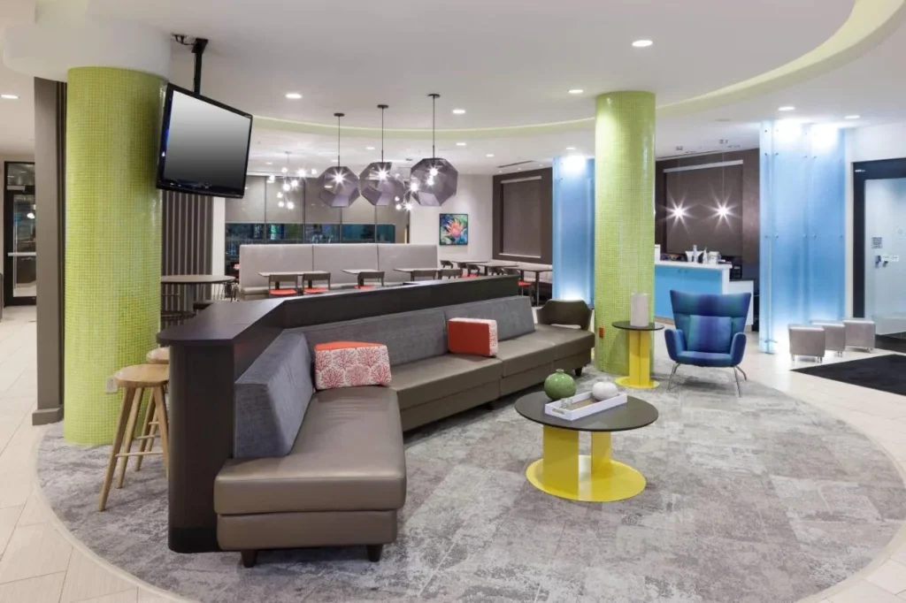 Circular lobby lounge with sofas, wall TV and lime-green columns at SpringHill Suites Orlando at SeaWorld