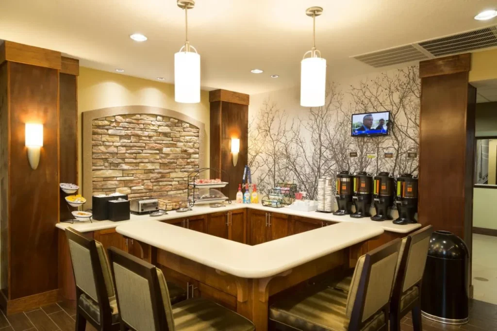 Cafetería con asientos, dispensadores de bebidas y un muro de piedra en Staybridge Suites Orlando at SeaWorld