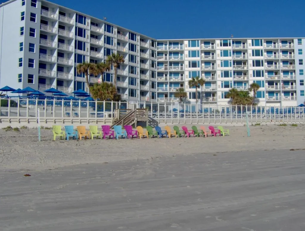 Colorful beach chairs on the sand in front of Islander Beach Resort oceanfront building in New Smyrna Beach