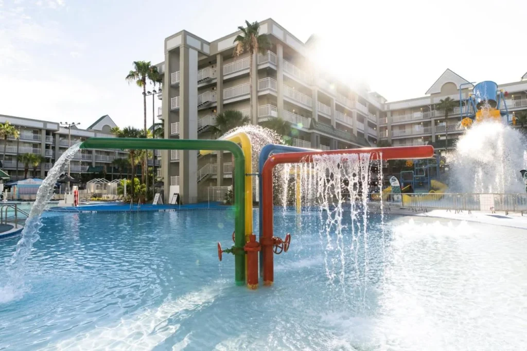 Colorful pipe fountains spraying into the pool beside suite buildings at Holiday Inn Resort Orlando Suites