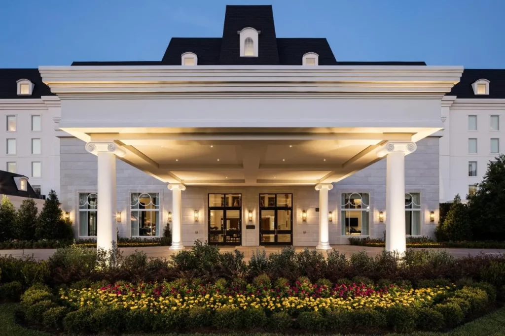 Entrada porte-cochere con columnas y macizos de flores al atardecer en The Equestrian Hotel en Ocala