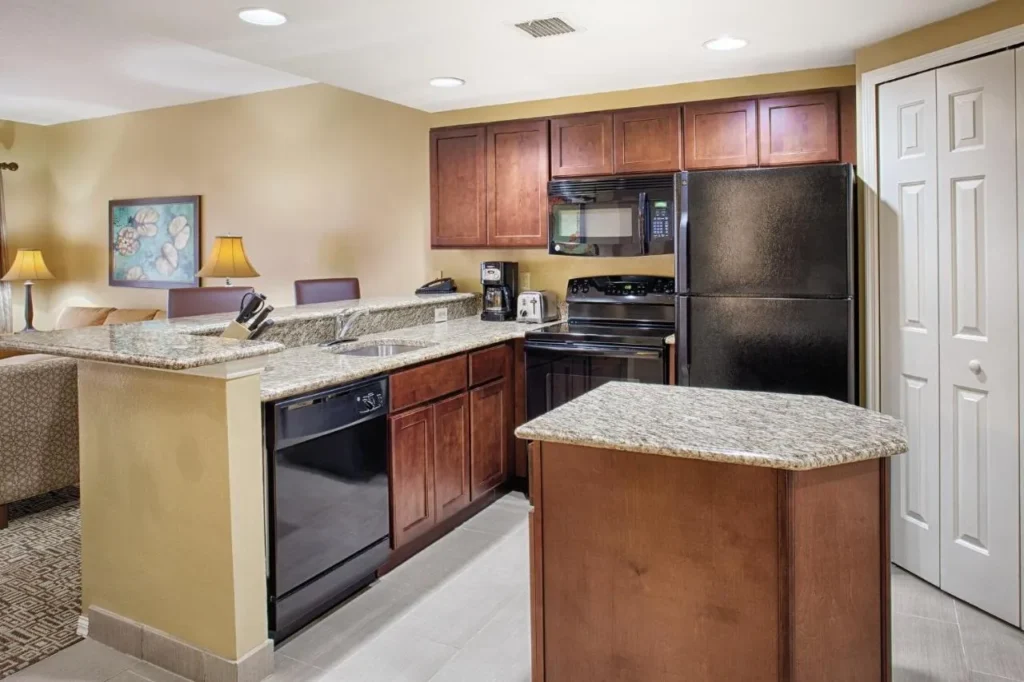 Condo kitchen with wood cabinets, granite island and black appliances at Club Wyndham Cypress Palms
