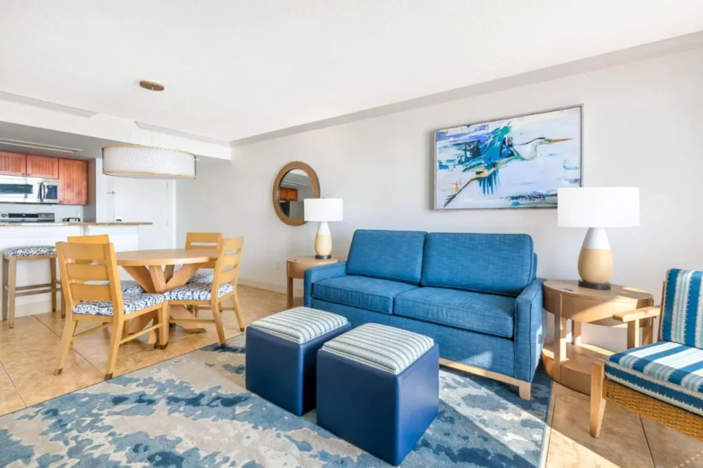 Condo salón con sofá azul, mesa de comedor y cocina en The Cove en Ormond Beach
