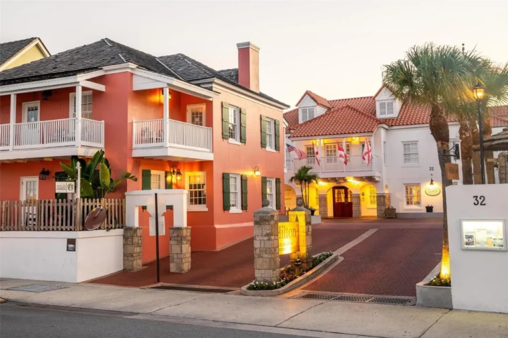 Coral and white Spanish Colonial-style buildings and entrance of Hilton St. Augustine Historic Bayfront at dusk