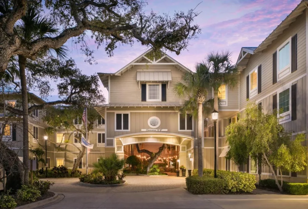 Cottage-style entrance and porte-cochere under oak trees at dusk at Hampton Inn New Smyrna Beach