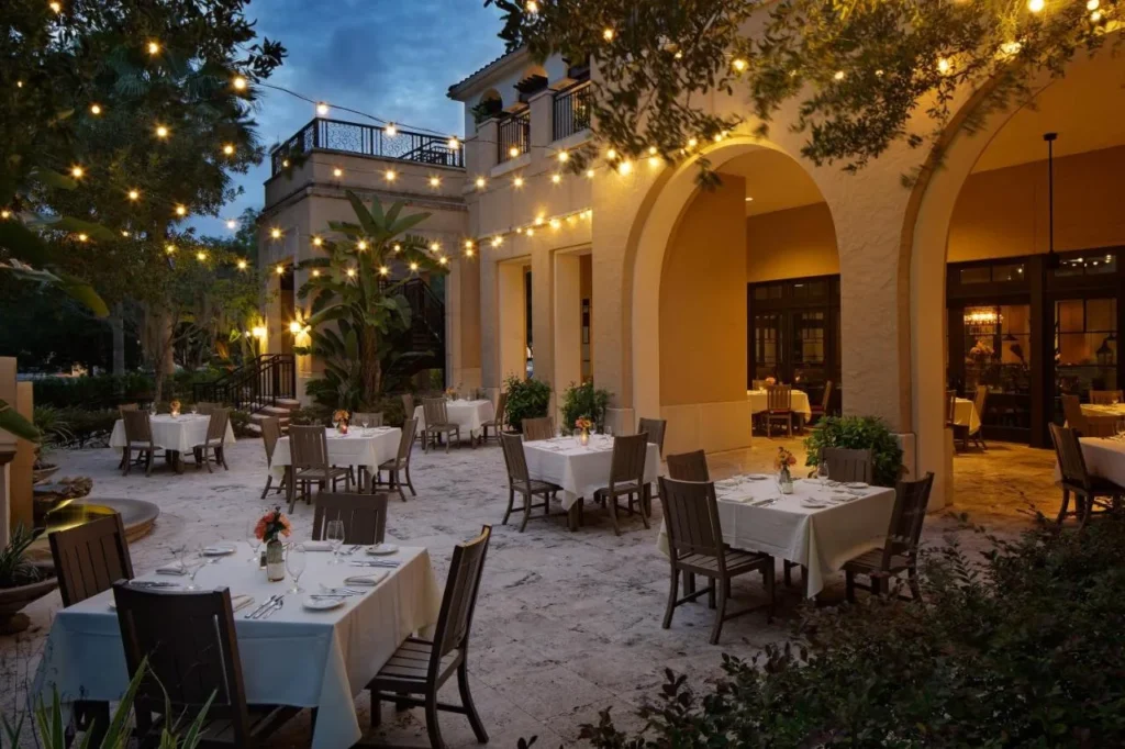 Courtyard dining terrace under string lights and arches at The Alfond Inn, Winter Park
