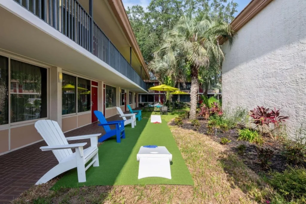 Courtyard con sillas Adirondack y tablas de cornhole en Ramada by Wyndham Kissimmee Gateway