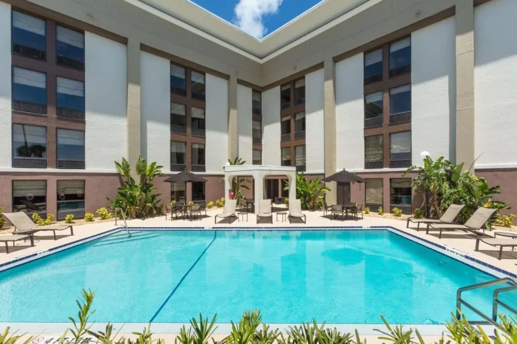 Courtyard piscina al aire libre con tumbonas y sombrillas en el Hampton Inn Daytona Speedway-Airport