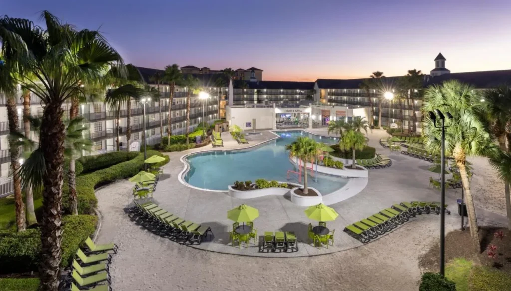 Courtyard pool with green loungers and umbrellas at dusk at Avanti International Resort