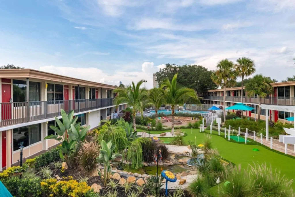 Courtyard con un putting green, jardines y la piscina entre las alas de dos pisos en Ramada Kissimmee Gateway