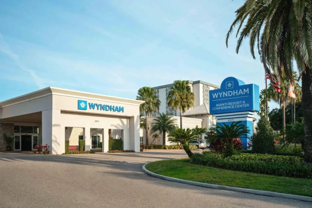 Covered entrance and blue Wyndham sign with the guest tower behind at Wyndham I-Drive Avanti Resort