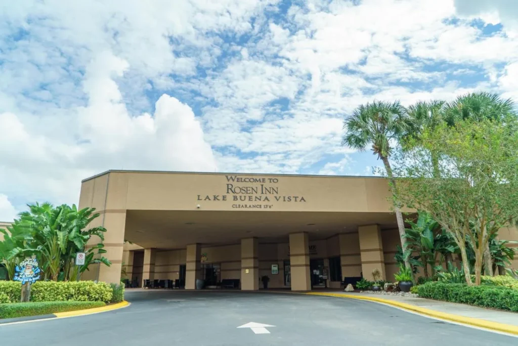 Covered entrance drive with the Welcome to Rosen Inn Lake Buena Vista sign and palm trees