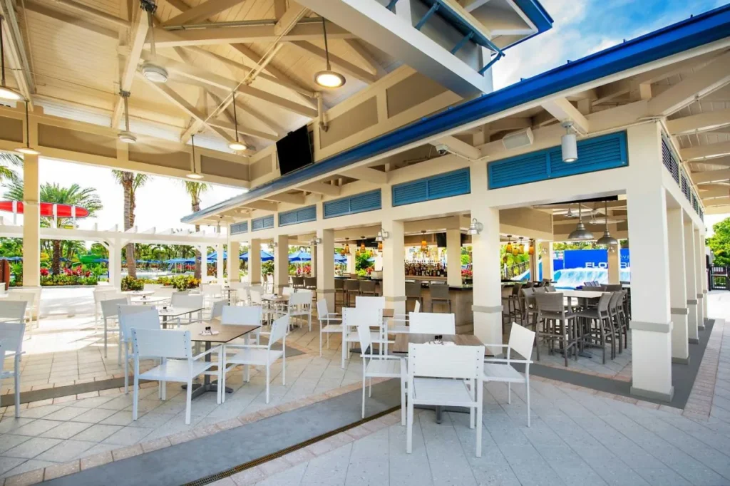 Bar al aire libre cubierto y patio de comedor con mesas y sillas blancas en The Grove Resort