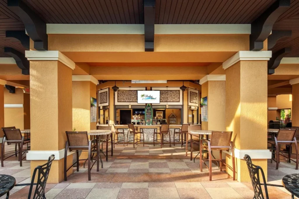 Bar de piscina al aire libre cubierto con mesas altas y taburetes de bar en Floridays Resort Orlando