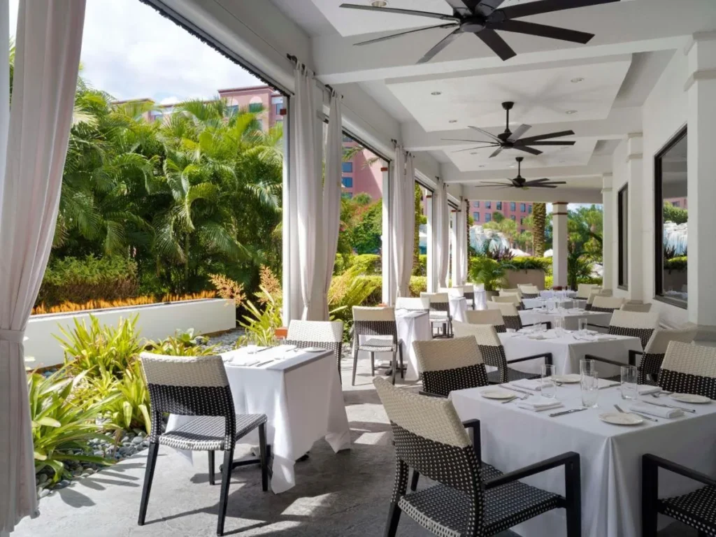 Comedor cubierto con manteles blancos y plantas tropicales en Caribe Royale Orlando