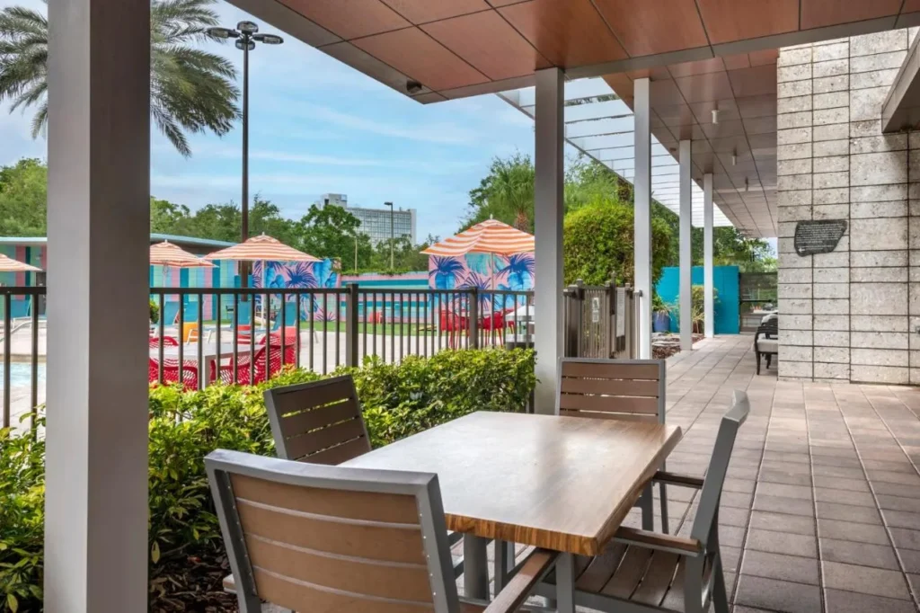 Mesa de patio cubierta junto al área de la piscina cercada en Holiday Inn Orlando Disney Springs