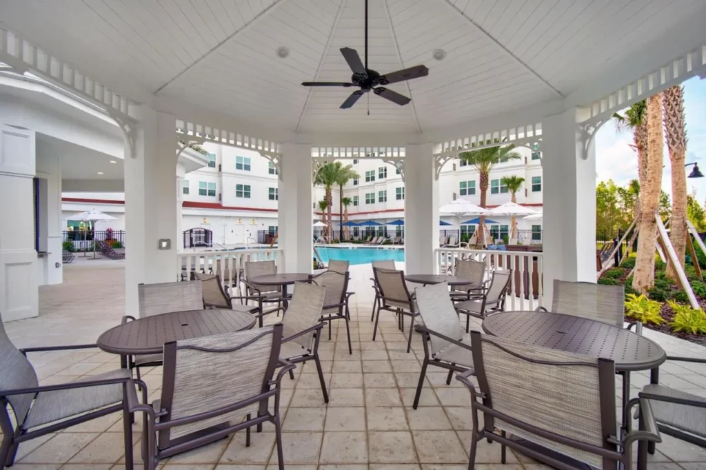 Mesas cubiertas frente a la piscina en el Residence Inn Orlando at Flamingo Crossings Town Center