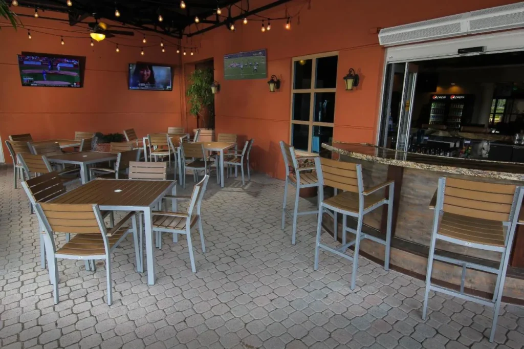 Covered pool bar patio with tables, bar chairs and sports TVs at Westgate Palace