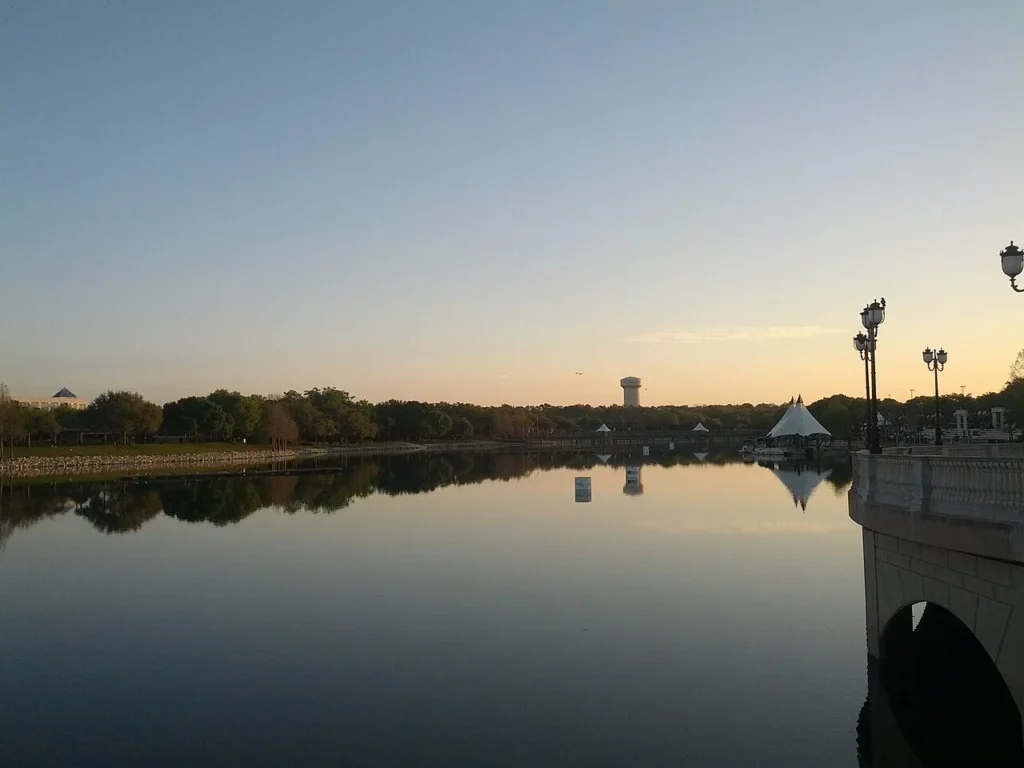 Grullas Roost Lago al amanecer con postes de luz, un puente de piedra y un pabell&oacute;n de tienda blanca