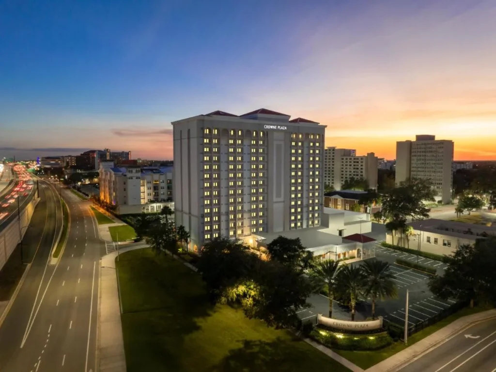 Crowne Plaza Orlando Torre del centro iluminada al atardecer junto a la I-4, con su letrero de entrada y estacionamiento