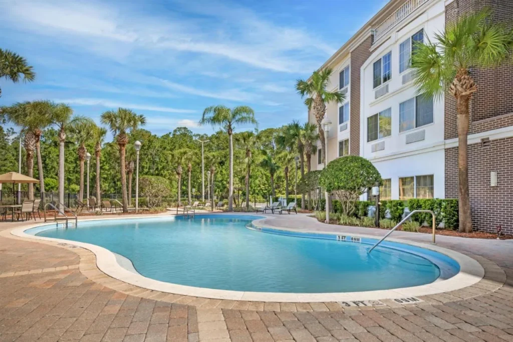 Piscina exterior curvada y palmeras en el Best Western Plus Orlando Lake Buena Vista South
