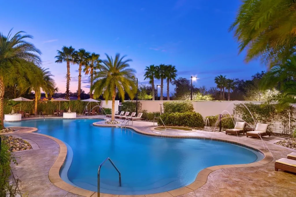 Curved outdoor pool framed by palm trees at dusk at The Westin Lake Mary, Orlando North