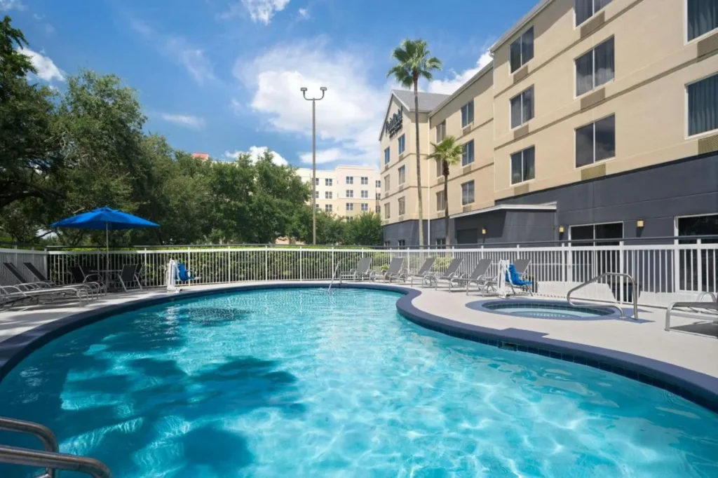 Piscina exterior curvada, ba&ntilde;era de hidromasaje y tumbonas junto al edificio Fairfield Inn Orlando Airport