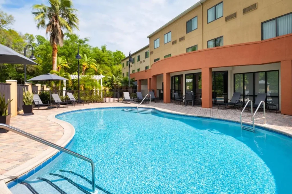 Piscina exterior curvada con tumbonas y palmeras en el Fairfield Inn & Suites Orlando Ocoee