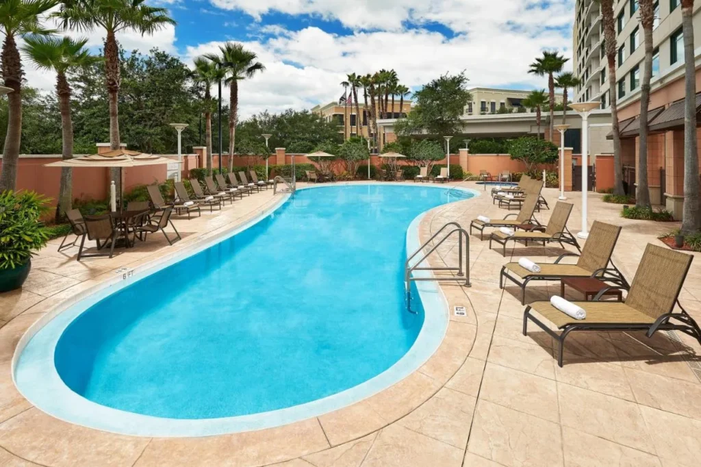 Piscina exterior curva con tumbonas y palmeras junto a la torre Orlando Marriott Lake Mary