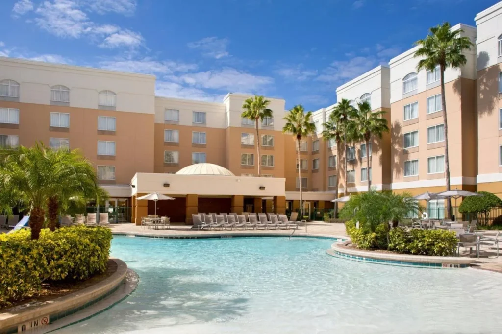 Piscina exterior curva con tumbonas y sombrillas en el SpringHill Suites Orlando Lake Buena Vista