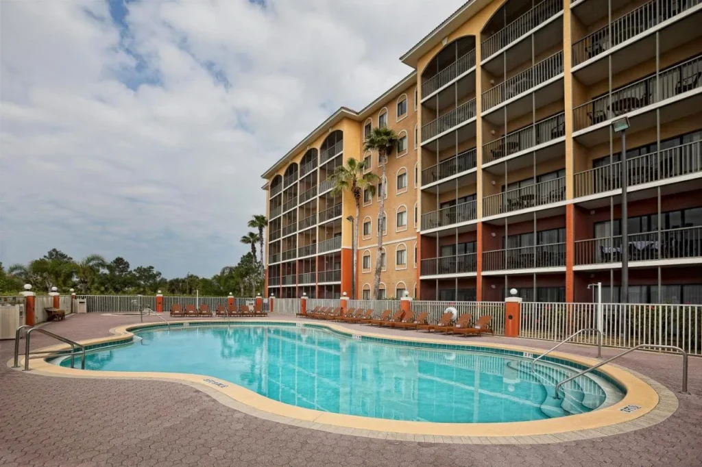 Curved outdoor pool with loungers below a villa building with screened balconies at Westgate Towers Resort