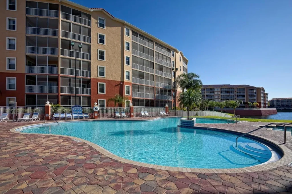 Curved outdoor pool with loungers beside a villa building at Westgate Town Center Resort