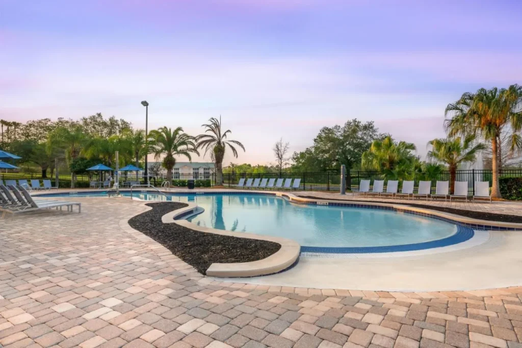 Piscina curva con una entrada inclinada y tumbonas al atardecer en Mystic Dunes Resort