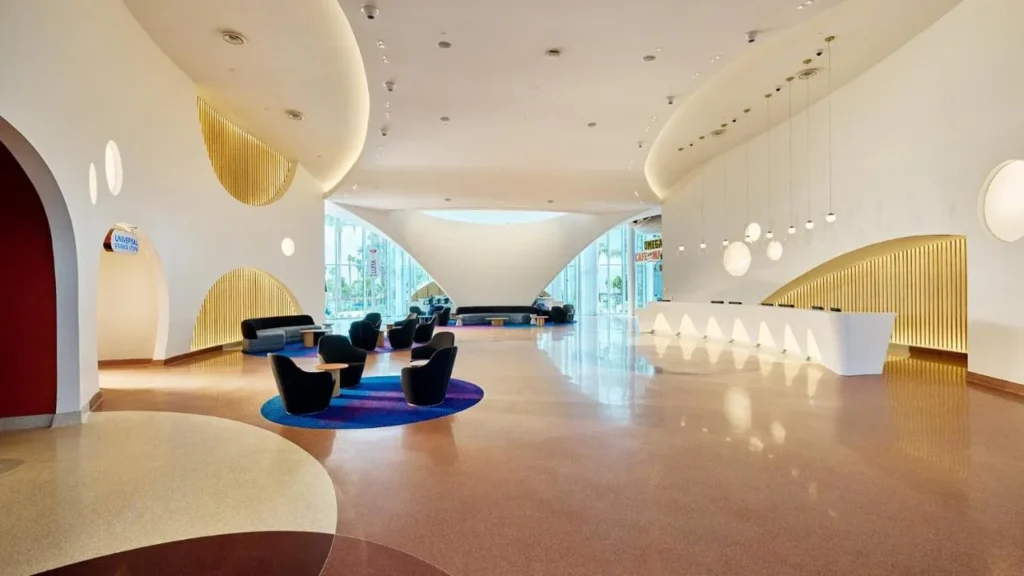 Lobby blanco curvado con detalles dorados, tumbonas y recepción en Universal Terra Luna Resort