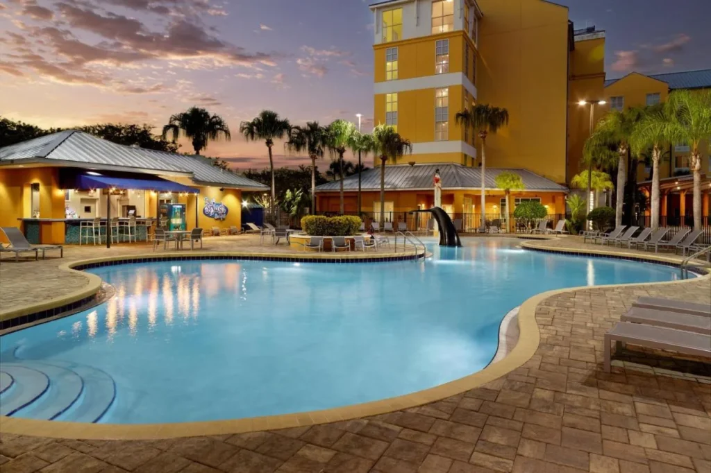 Piscina curva al atardecer con una escultura de cola de orca y un bar en la piscina, SpringHill Suites Orlando at SeaWorld