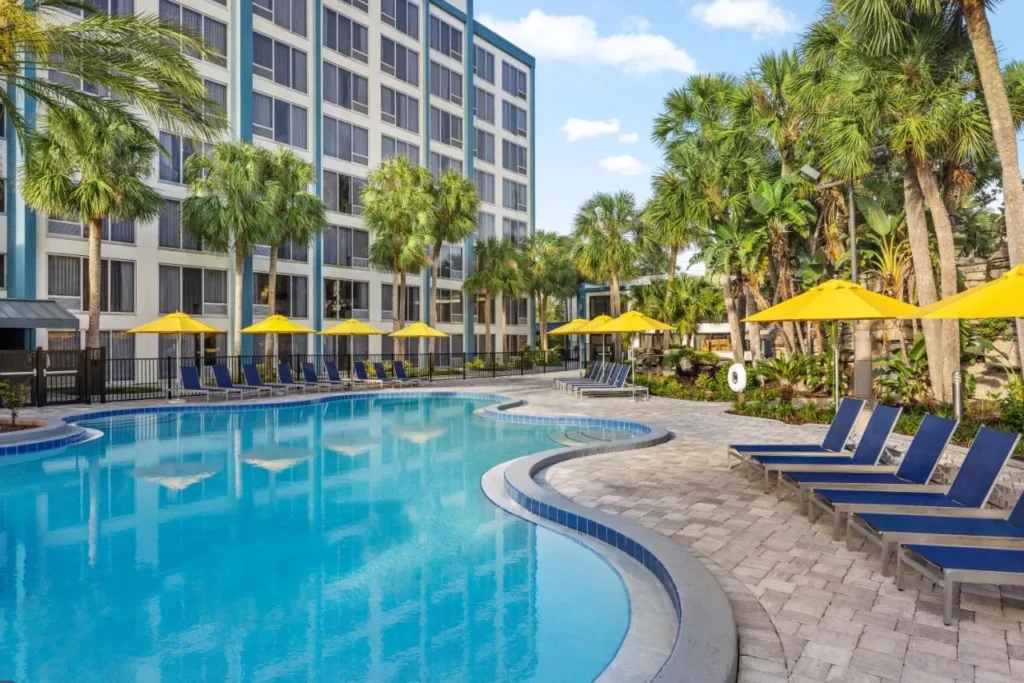 Piscina curva con sombrillas amarillas junto al ala del hotel en Delta Hotels Orlando Celebration