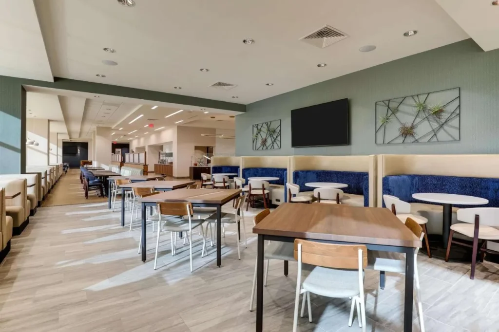 Dining area with blue booths and wooden tables at Drury Plaza Hotel Orlando