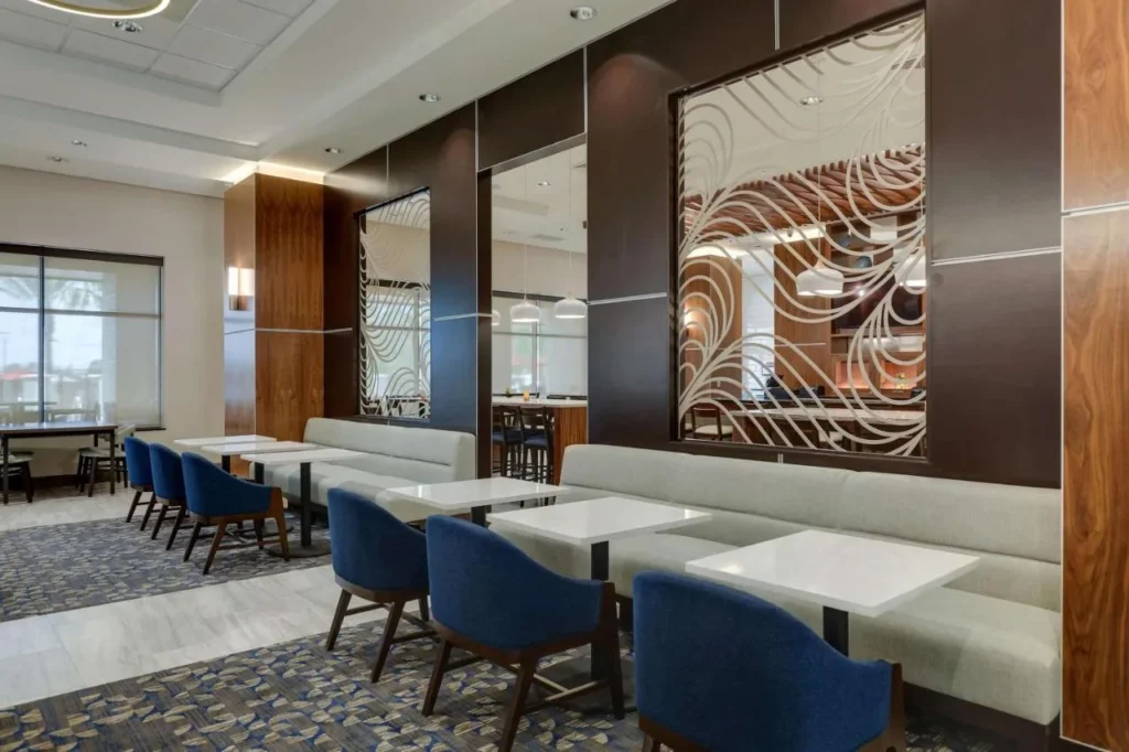 Dining area with blue chairs, white tables and long banquettes at Drury Plaza Hotel Orlando