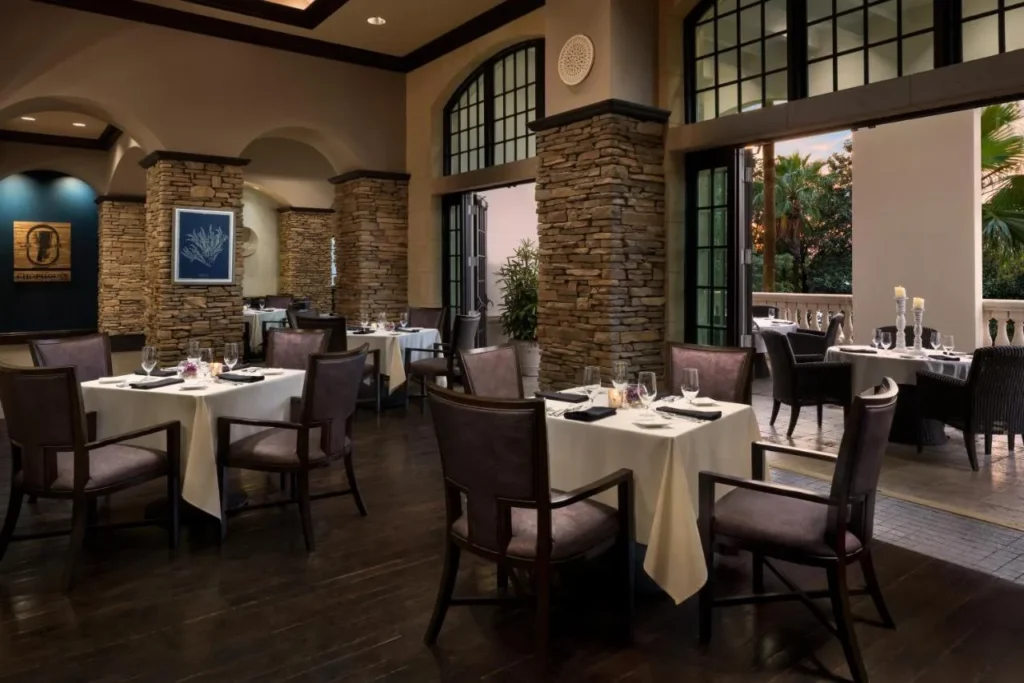 Dining room with white tablecloths, stone columns and open doors at 7593 Chophouse, Reunion Resort