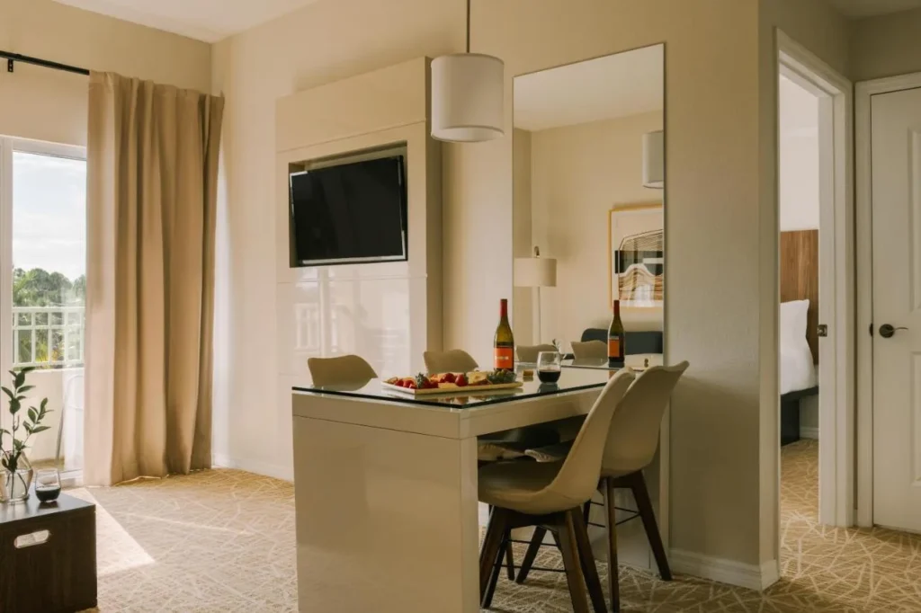 Mesa de comedor, sillas y TV de pared en una suite en The Point Hotel & Suites