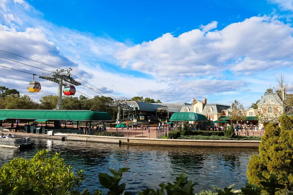 Disney Skyliner gondolas passing over the canal beside EPCOT's International Gateway entrance on a sunny day