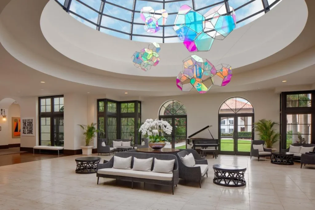 Domed conservatory lobby with grand piano and hanging glass artwork at The Alfond Inn