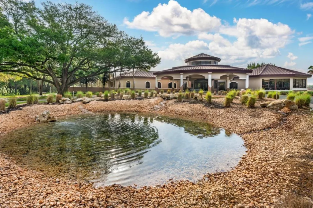 Complejo abovedado m&aacute;s all&aacute; de un estanque de roca ajardinado y robles vivos en Mystic Dunes Resort