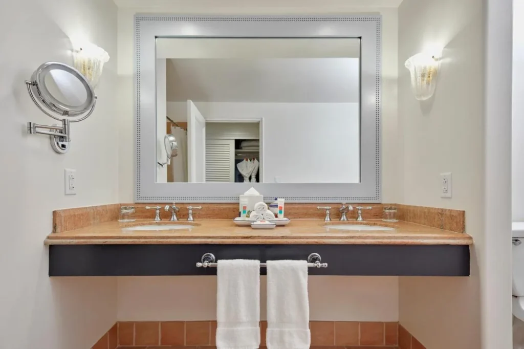 Vanidad de doble fregadero con un espejo enmarcado y apliques de pared en Loews Portofino Bay Hotel