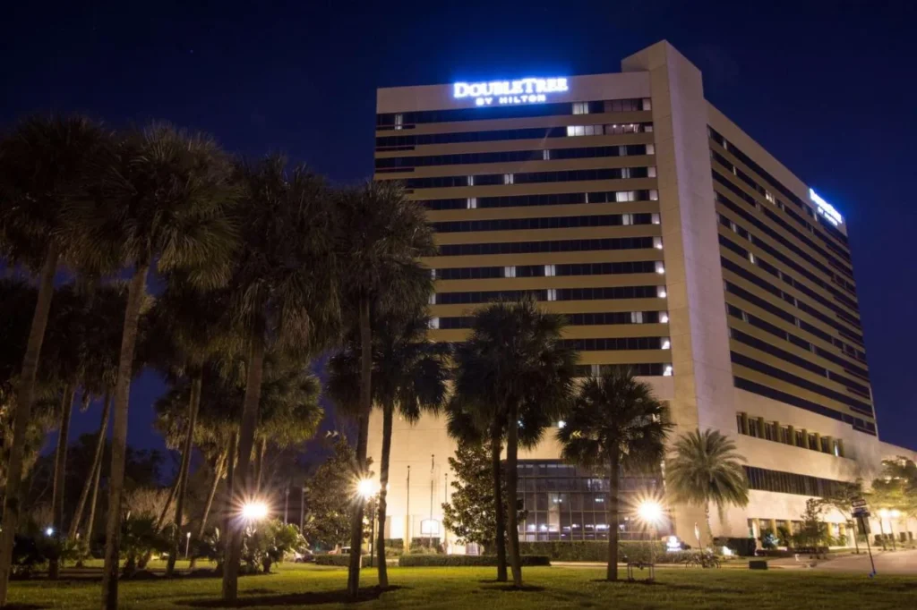 DoubleTree by Hilton Orlando Downtown tower lit up at night behind tall palm trees