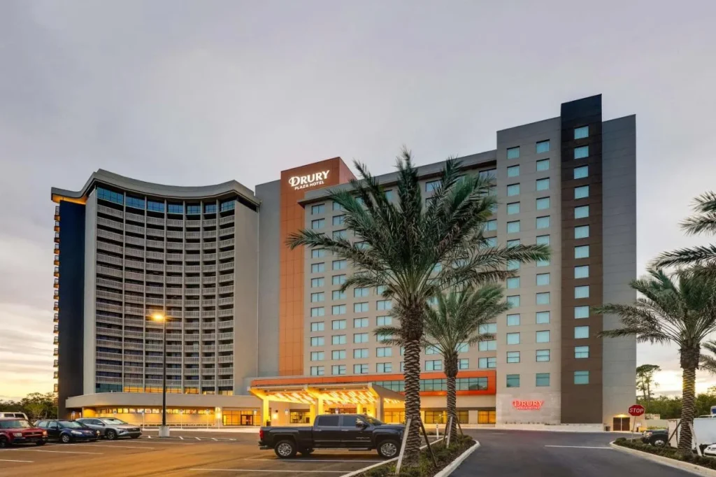 Drury Plaza Hotel Orlando towers, palm trees and lit entrance canopy at dusk near Disney Springs
